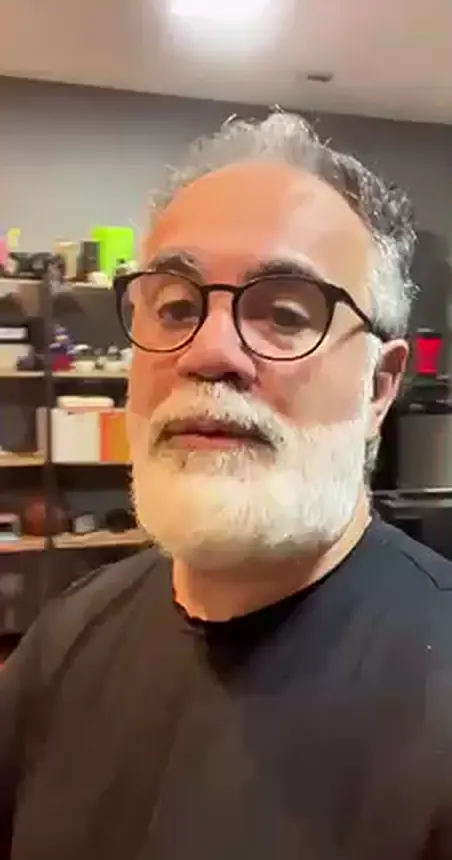 Bruno gravando com o celular no escritório, de camiseta preta